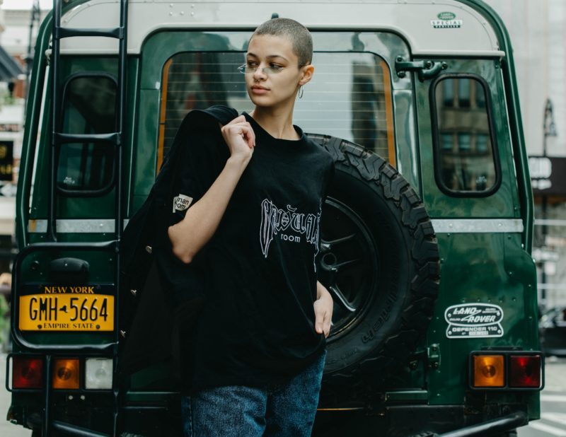 Woman with shaved head standing neat black vehicle