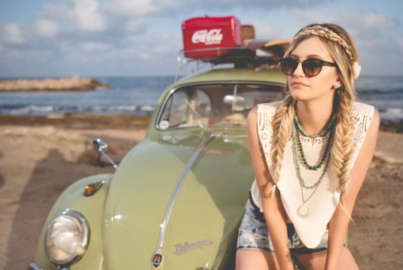 Woman with fishtail braids sitting in front of a car