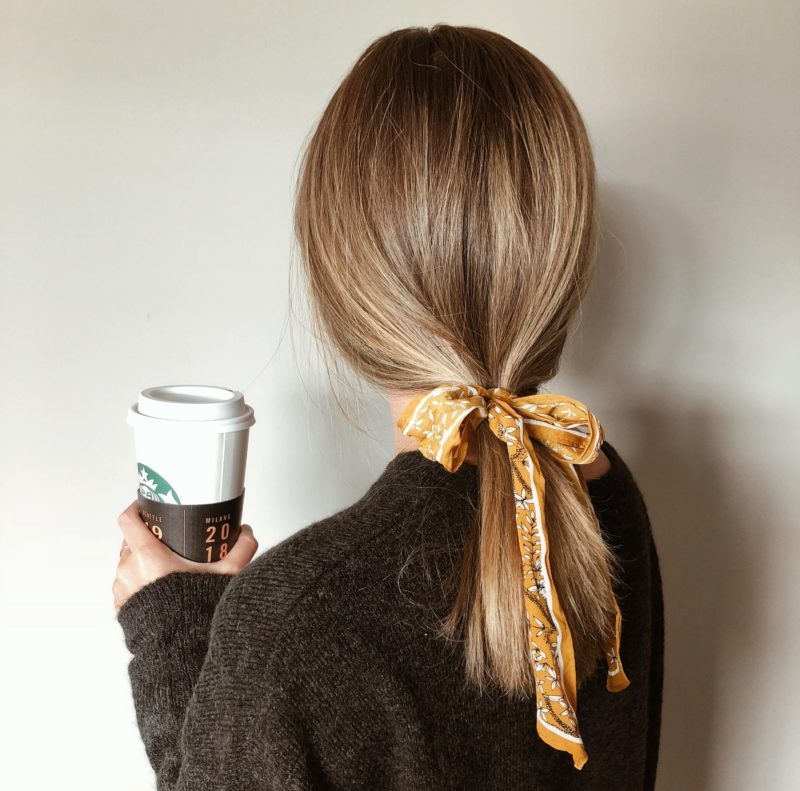 Woman in black sweater holding a coffee cup