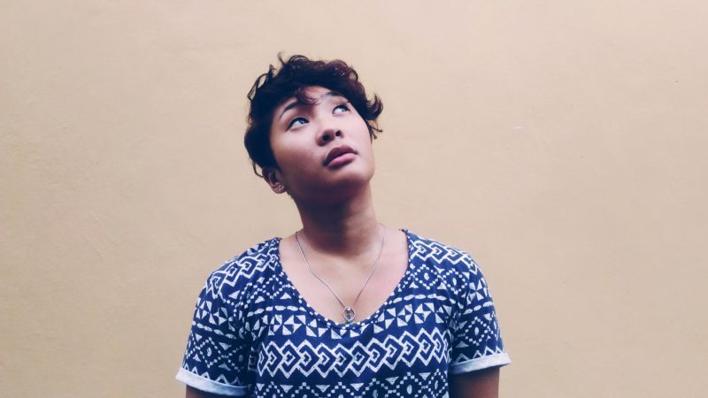 Woman with short hair wearing black and white shirt looking above