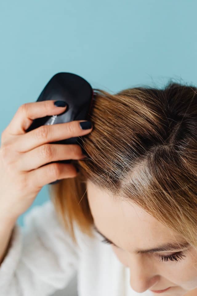 person brushing hair with a hair brush