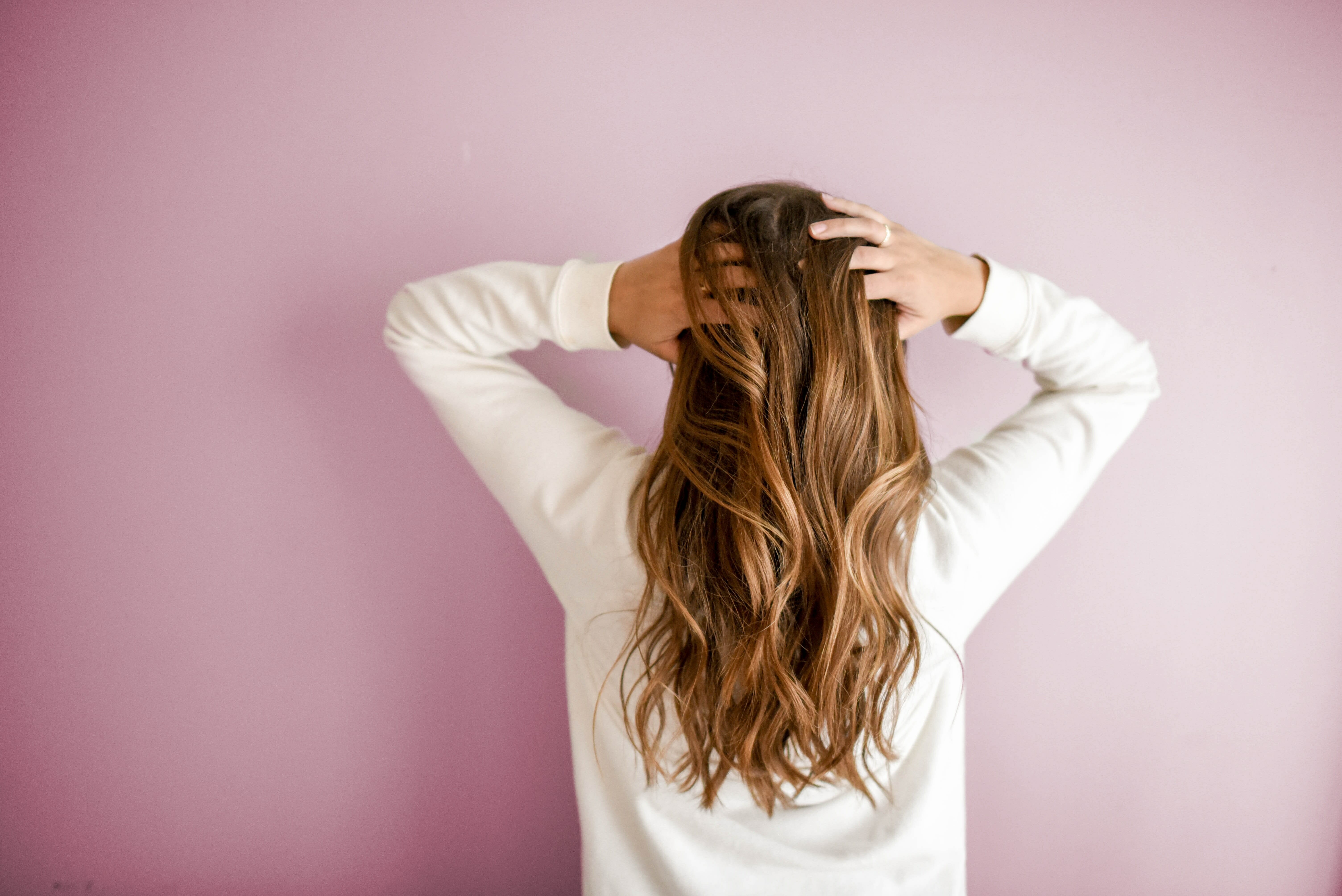 woman with long hair facing the wall and touching her head