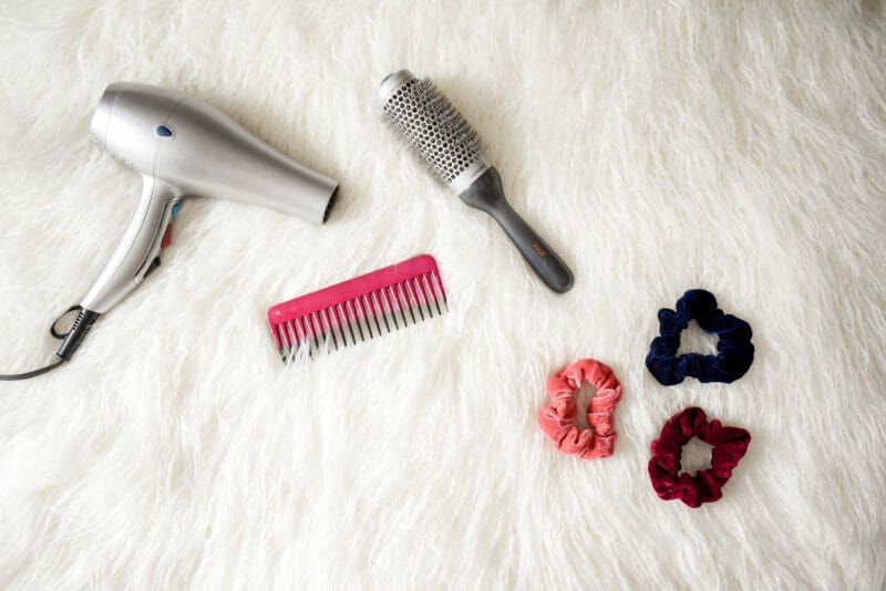 blow dryer, comb and brush accessories in fluffy background
