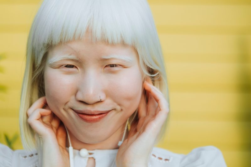 Woman with white hair and white eyebrows with bangs and a bob cut